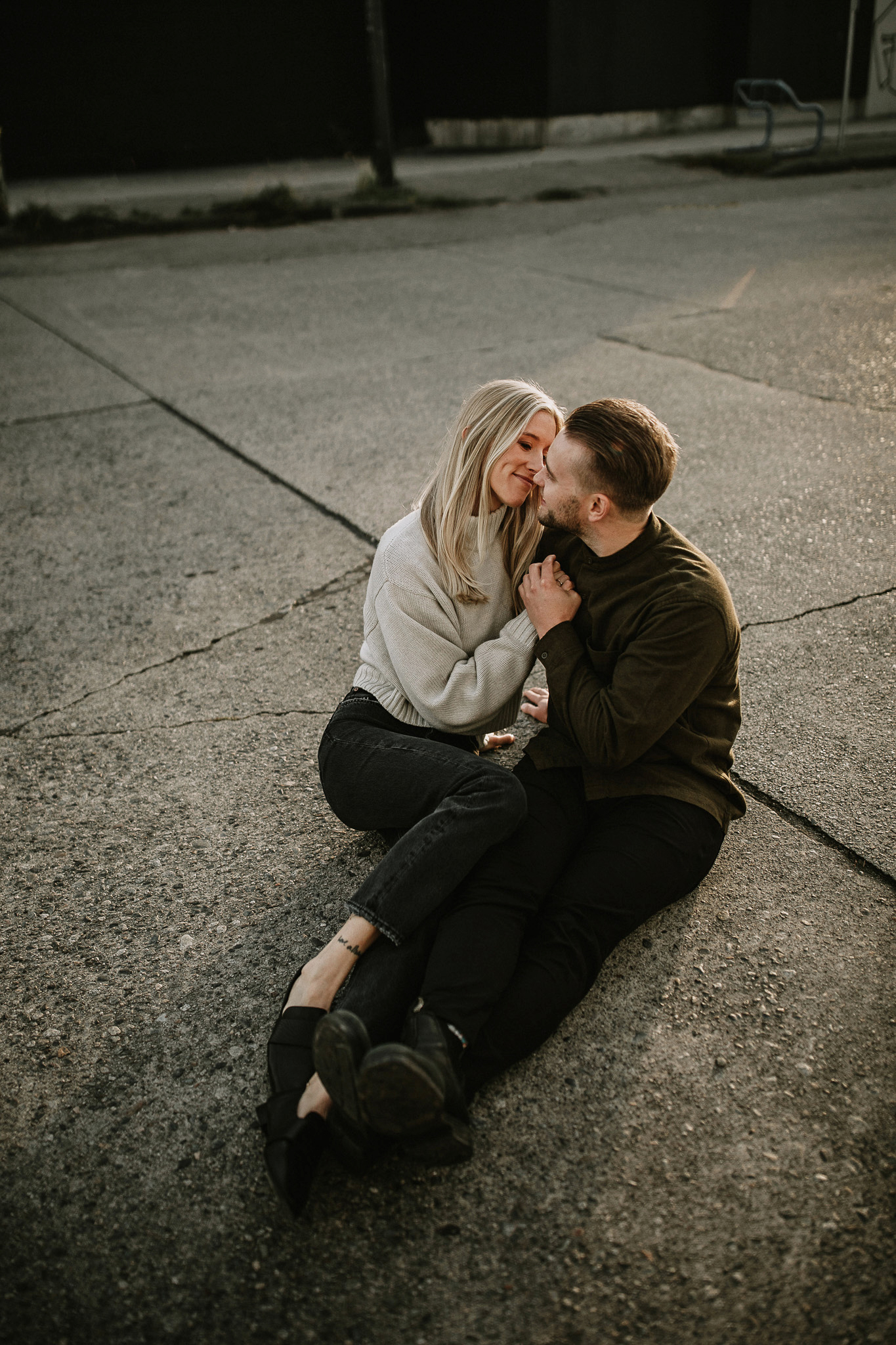 Golden hour sunset photos of a couple siting in the middle of the road kissing